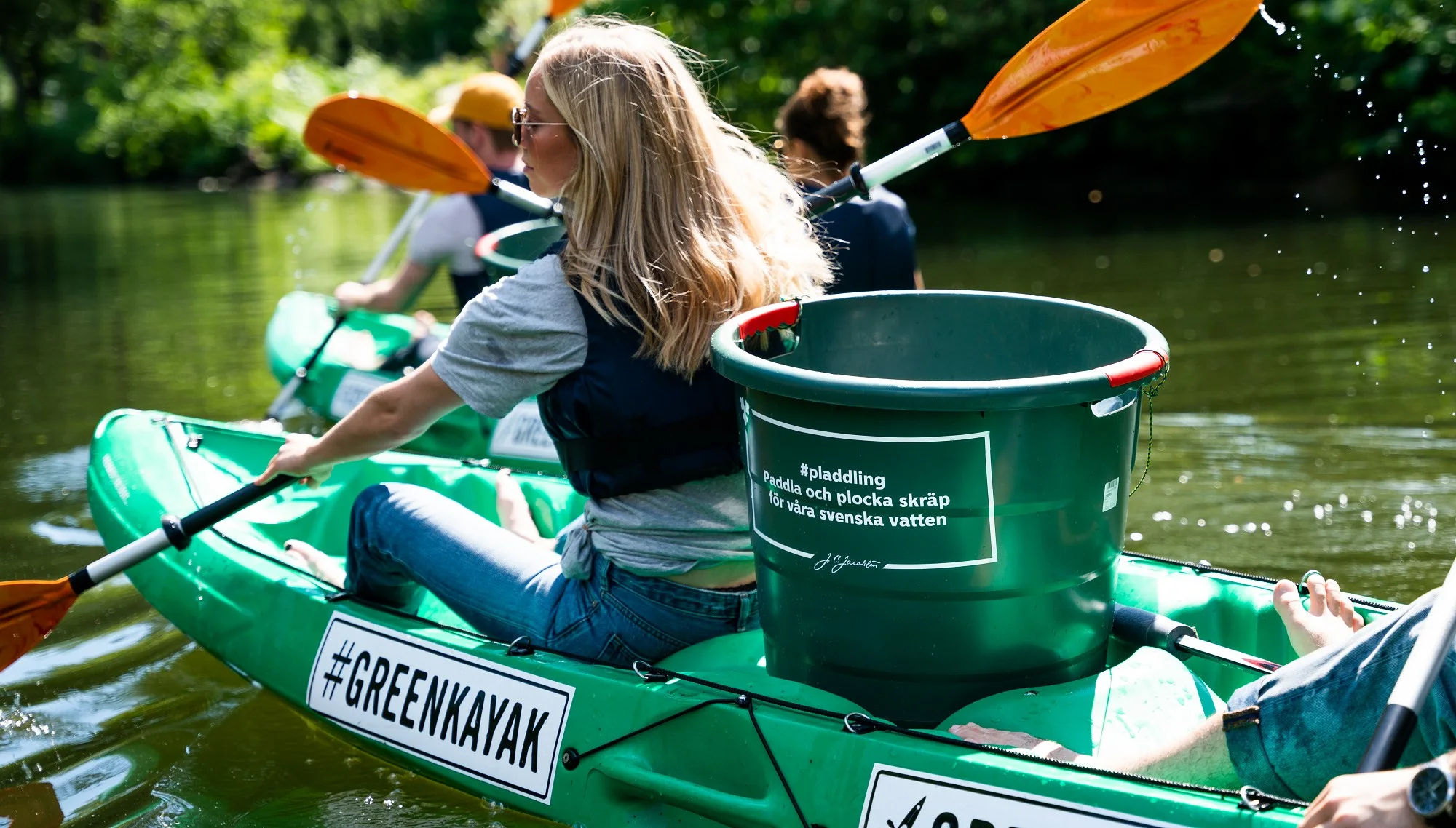 Kayak with a bucket marked #pladdling – paddle and pick up litter for Swedish waters